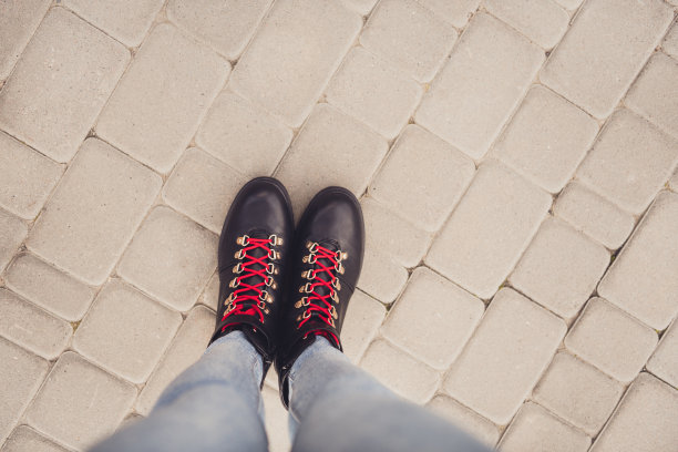 上面高角度第一人称观看裁剪照片的女孩腿穿黑色皮靴鞋与红色蕾丝在石头路图片下载