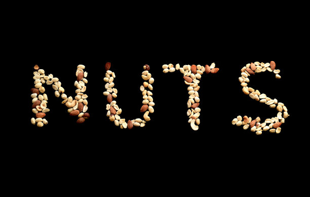 文字艺术“坚果”由杏仁、榛子、花生和腰果混合而成，以黑色为背景图片下载