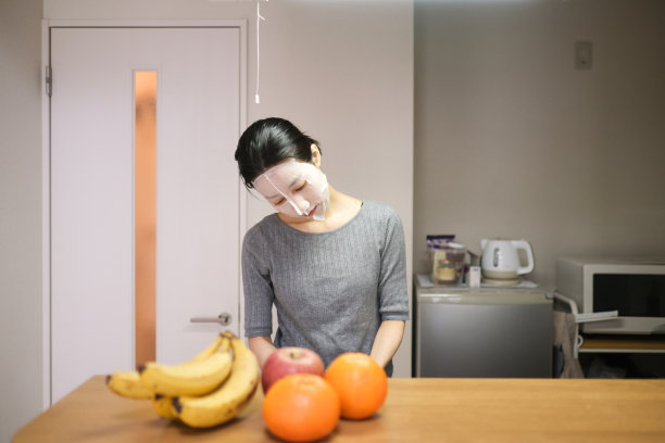 年轻女子戴着面膜，在厨房做饭图片下载