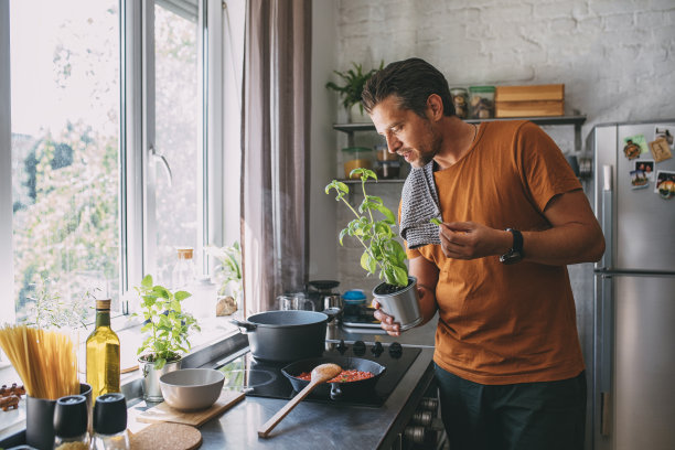 英俊的年轻人在做饭时采摘罗勒叶图片下载