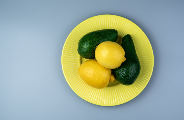 牛油果，柠檬，黄色盘子，灰色背景。顶部视图与空间复制图片下载