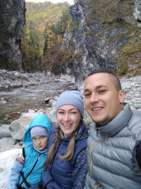 游客在徒步旅行后休息，用手机自拍。徒步旅行时手机里的照片。家庭旅行。人的环境由山、水、溪组成。男人和女人都有徒步旅行背包。图片下载