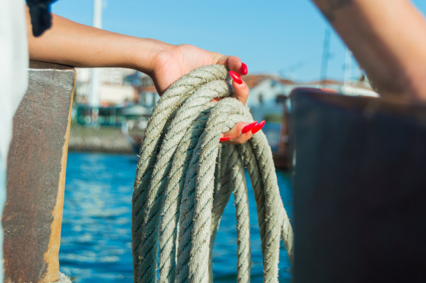 一个女人的手抓住一条旧船的绳子。图片下载