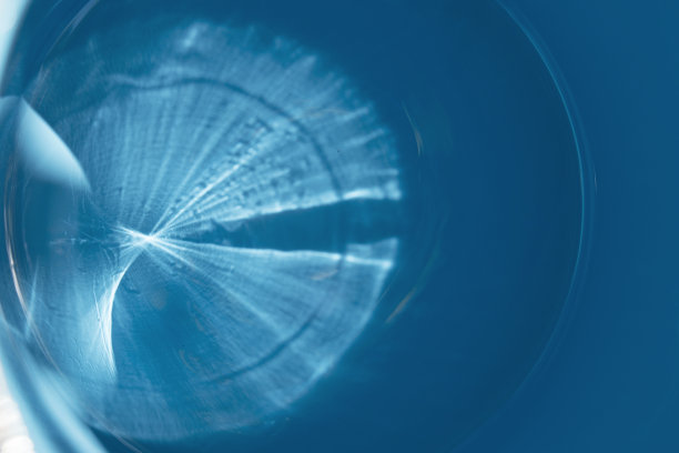 太阳光在蓝色涂料表面的光学折射。模糊图像的圆形点在左边的一个梯度。软选择聚焦。图形图像，抽象背景。图片下载