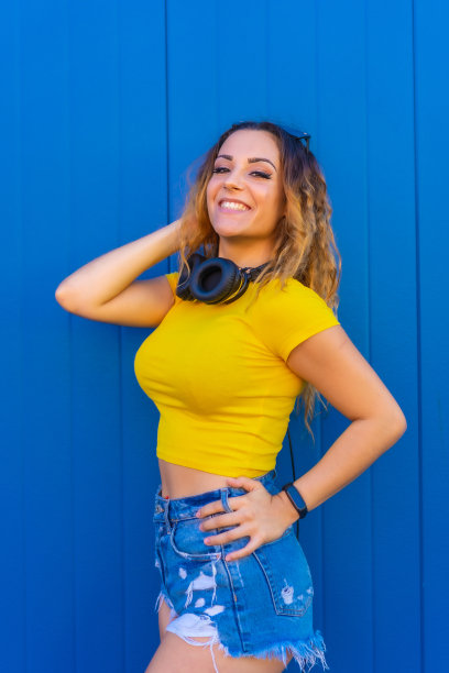 生活方式，金发白种女孩，黄色t恤，蓝色背景。带耳机的Dj女孩为电子音乐，家庭聚会或会议海报宣传照片图片下载