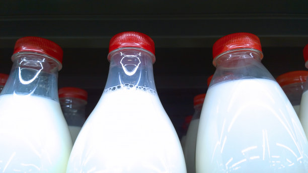 鲜奶装在带有红色瓶盖和黑色背景的塑料瓶中。乳品店。超市货架上。食品和零售业。自然的农民的产品。食品杂货店购物。健康饮食。图片下载
