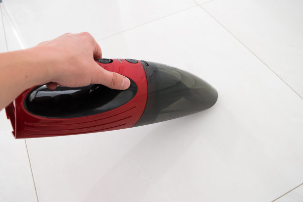 红色汽车吸尘器，手拿着汽车吸尘器，清扫着地板图片下载