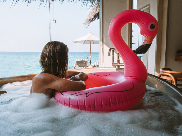 年轻女子在海边的豪华别墅里和充气火烈鸟一起洗澡图片下载
