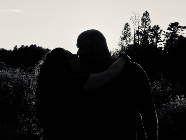 一对情侣在户外亲吻拥抱的剪影。图片下载