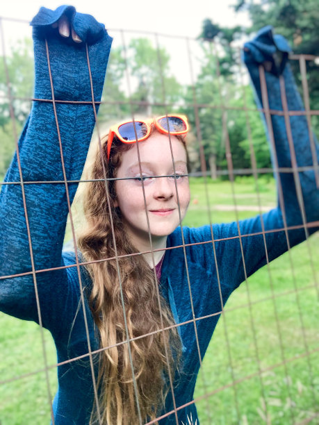 可爱的红发少年在户外玩耍和挂在篱笆上。图片下载