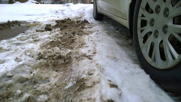 车轮附近有脏脏的雪。冬天路上有泥浆、盐和化学品。城市生态问题。保护和清洗车辆的概念。环境的对话。开车。汽车轮毂罩。图片下载