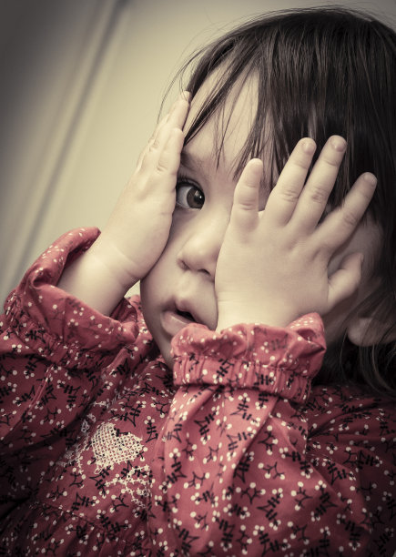 小女孩躲在她的手后面图片下载