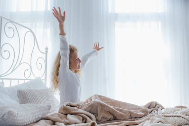 侧视，小女孩在床上伸展着身体，小女孩在舒适的卧室里感觉很好图片下载