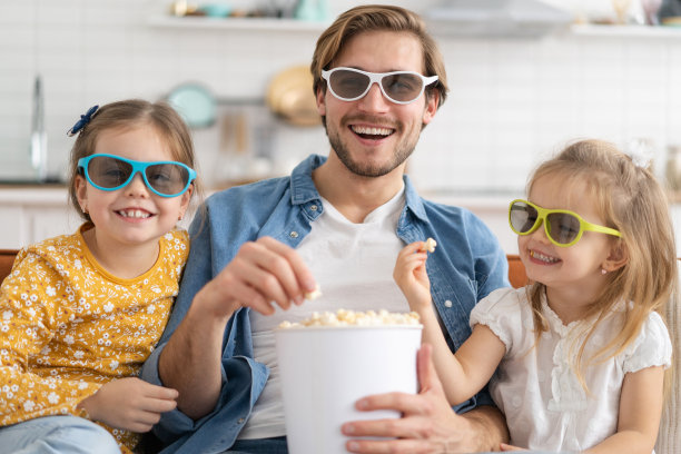 幸福的家庭在家里看电视，吃爆米花。图片下载