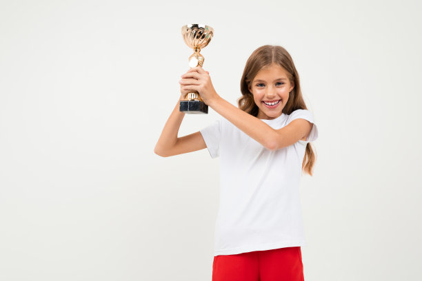 漂亮的女孩在白色和红色的服装显示她的金杯和欣喜孤立在白色的背景图片下载