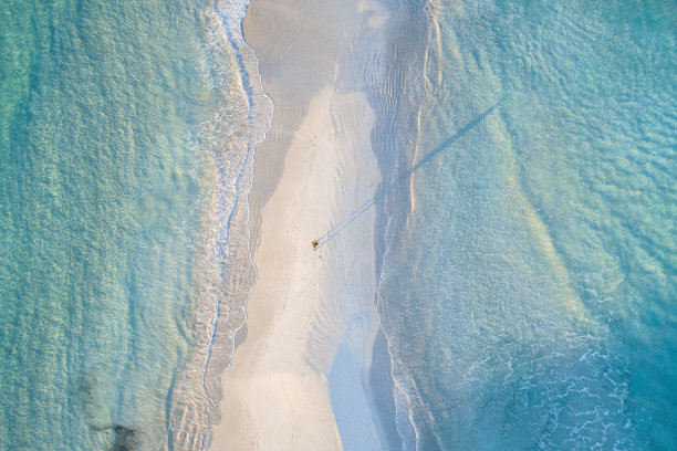 风景如画的海岸线航拍照片，蓝绿色的海洋和沿着白色沙滩行走的人图片下载