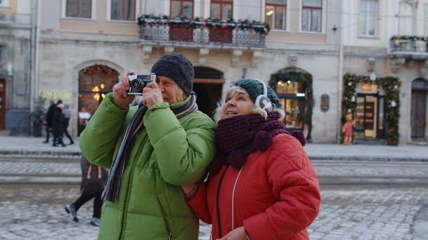 老夫人丈夫在复古相机上拍照，走在冬天的城市街道上图片下载