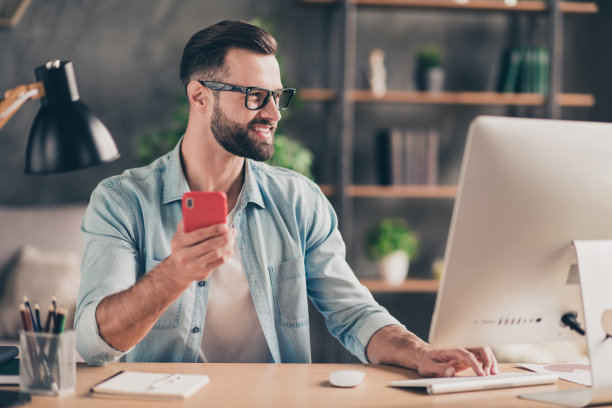 照片肖像的一个微笑的家伙拿着电话在桌子上工作在现代工业办公室室内图片下载