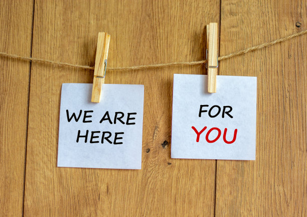 木制的晾衣夹和白纸。发短信说“我们在这里等你”。漂亮的木制背景。经营理念，复制空间。图片下载