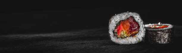 寿司、鱼和米饭放在黑色的木桌上图片下载