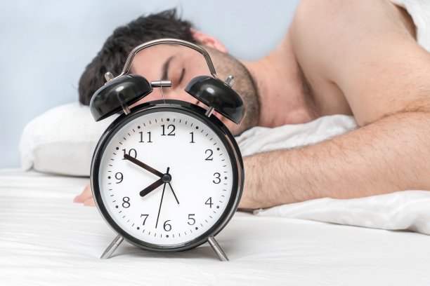 睡在枕头上的男人在起床前和闹钟在一起图片下载