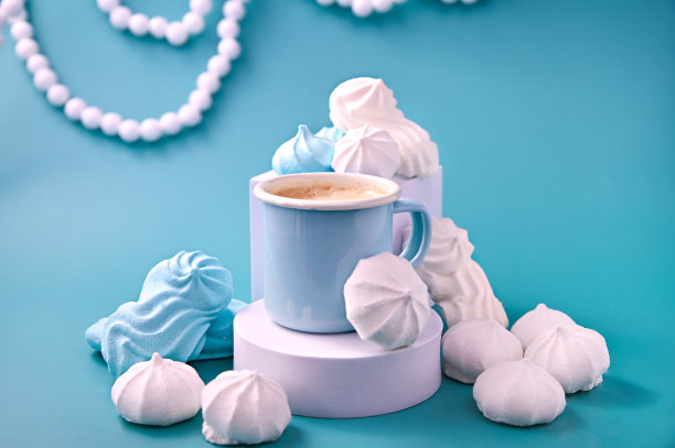 蓝色背景上有不同颜色的泡沫和蛋白糖霜的浓缩咖啡。酥皮。蛋白质和糖饼干的创意。高质量的照片。本空间图片下载