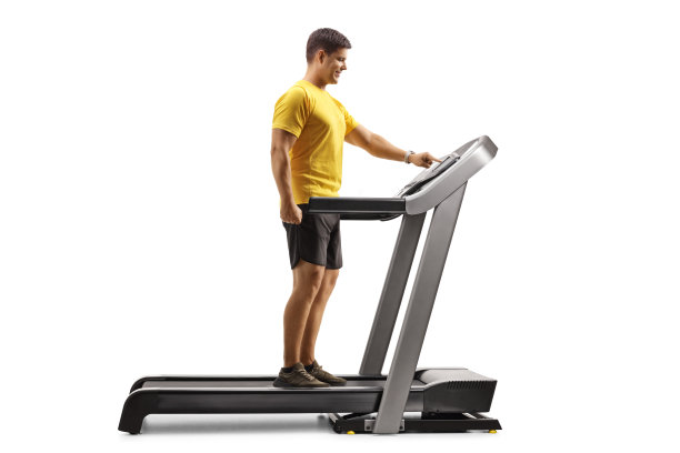 一个年轻人在跑步机上按一个按钮的全长侧面照片图片下载