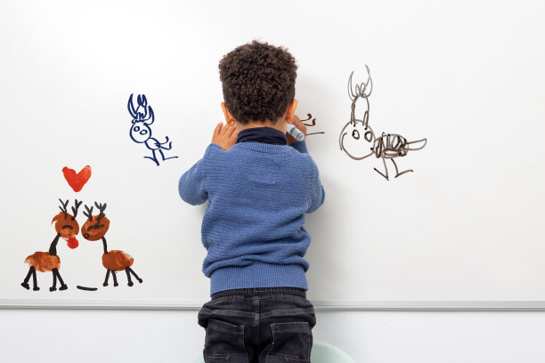 后视图的创造性的美国黑人孩子在白板上画画。图片下载