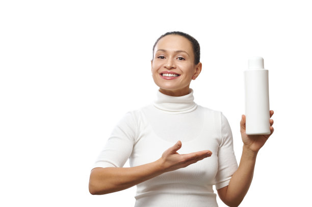 一个迷人微笑的女人展示一个美容产品的容器的照片。照片孤立在一个白色的背景图片下载