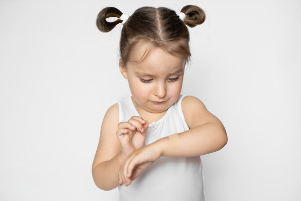 儿童手臂创面粘贴绷带，药物及急救。受伤的小女孩疼痛难忍，把医用胶布贴在手上。孤立在白色图片下载