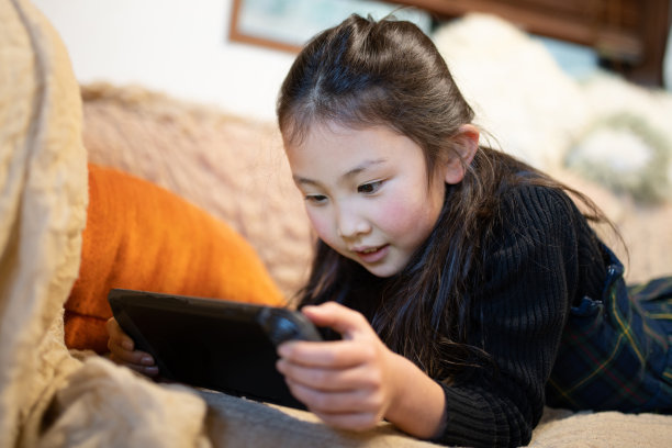 女孩在沙发上玩游戏图片下载