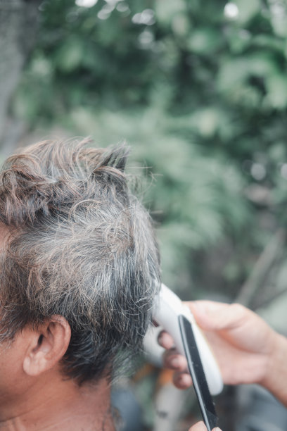 理发师正在为一位英俊的老人做时髦的发型。冠状病毒大流行限制期间的家庭美容图片下载