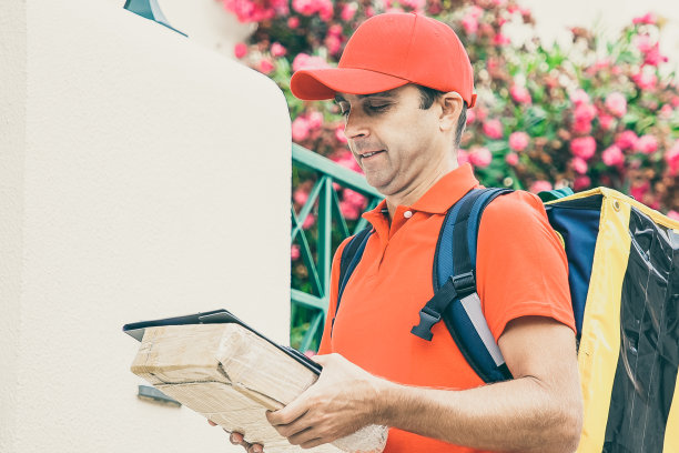 中年快递员拿着剪贴板和纸箱图片下载