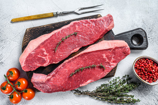 生臀肉或野鲑牛排放在木砧板上。白色背景。俯视图图片下载