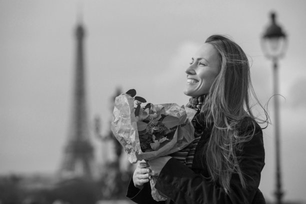 在巴黎的埃菲尔铁塔上，手持鲜花的美丽女子图片下载