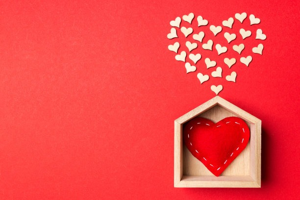 顶视图的红色纺织心脏在一个木制的房子装饰小心脏在彩色的背景。心的形状。甜蜜之家。情人节的概念图片下载