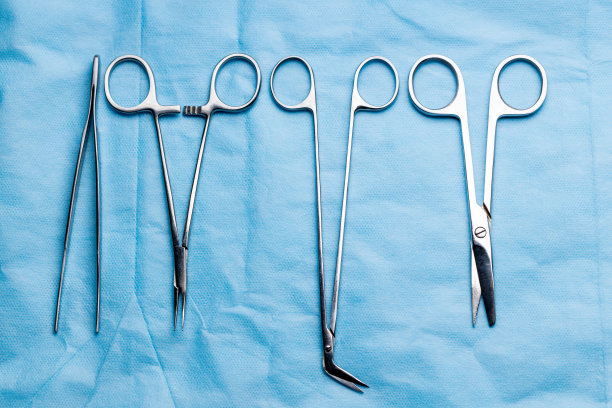 手术台上的手术台。医疗工具，如剪刀，手术刀，镊子，蓝色背景。手术的概念图片下载