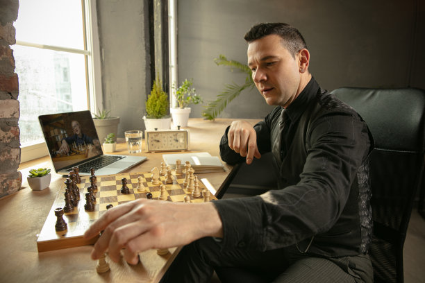 年轻的白人男子象棋选手在网上下棋使用笔记本电脑。图片下载