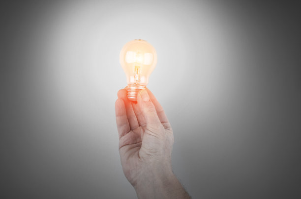 灰色背景上的手持灯泡图片下载