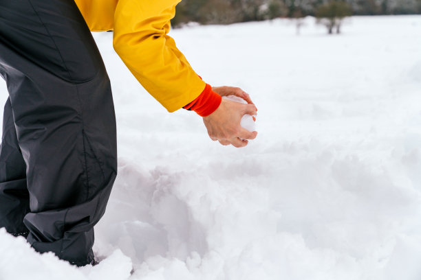 雪地上的照片，一些手正在用黄色外套雪球图片下载