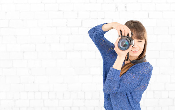 一个摄影师用相机遮住她的脸的肖像。图片下载