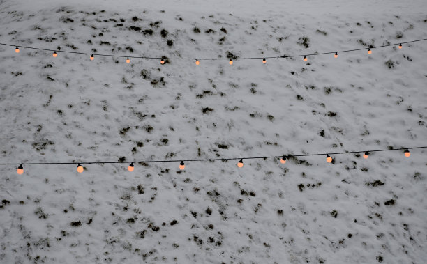 冬季滑雪场的雪坡上挂着一串串亮着的灯泡。这些彩灯用于庆典、婚礼和聚会舞会图片下载