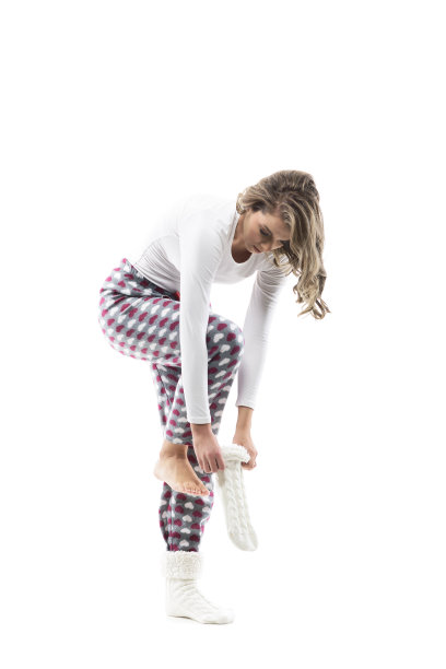 年轻的光着脚的女人穿着睡衣，穿上暖和的冬季针织袜子图片下载