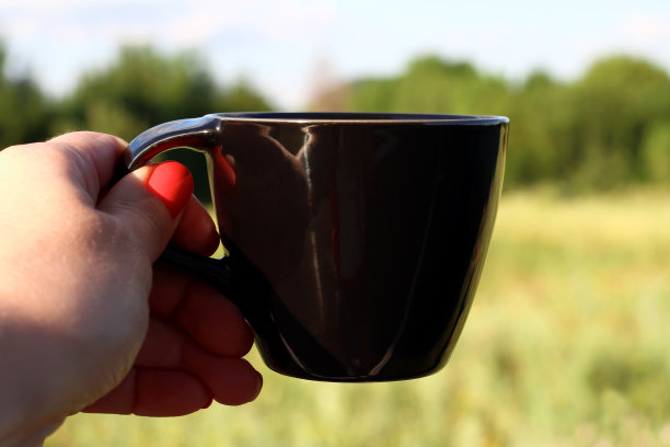 手拿黑杯，映衬着大自然。早上好图片下载