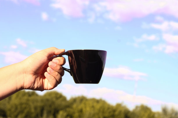 手拿黑杯，映衬着大自然。早上好图片下载