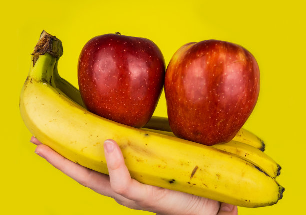 黄色背景上放着成熟的香蕉和红苹果。自然的香蕉皮。水果。图片下载