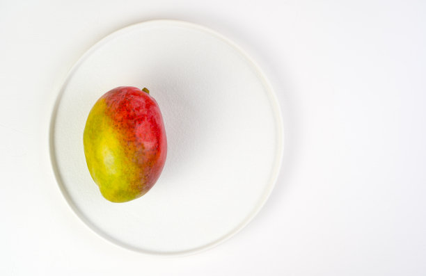 白色的盘子上放着多汁的熟透芒果，背景很亮图片下载