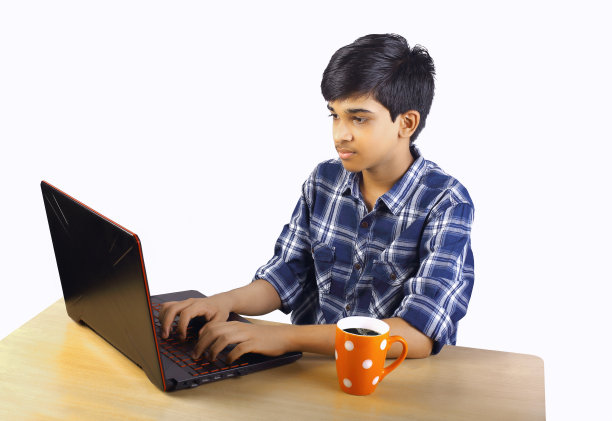 印度男孩拿着咖啡杯，用笔记本电脑图片下载