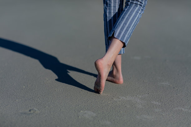女人的脚走在沙滩上，后脚趾尖。图片下载