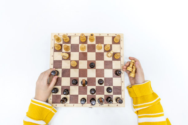 俯视图孩子的手正在木头棋盘上下棋，手里拿着棋子。图片下载